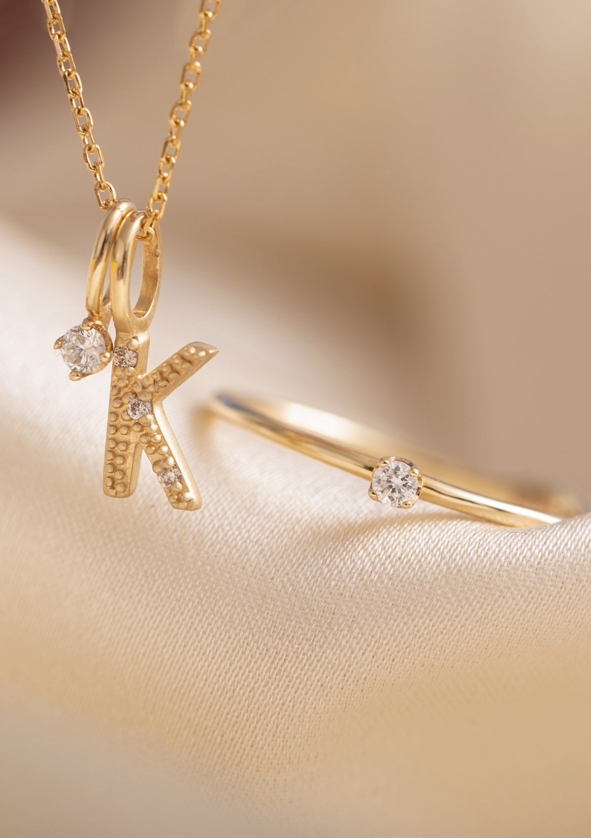 Smykker i 9 og 10 karat ægte guld fra Carré - Bogstavsvedhæng med K sat med diamanter, et vedhæng med diamant og en diamantring - diamant er aprils fødselssten