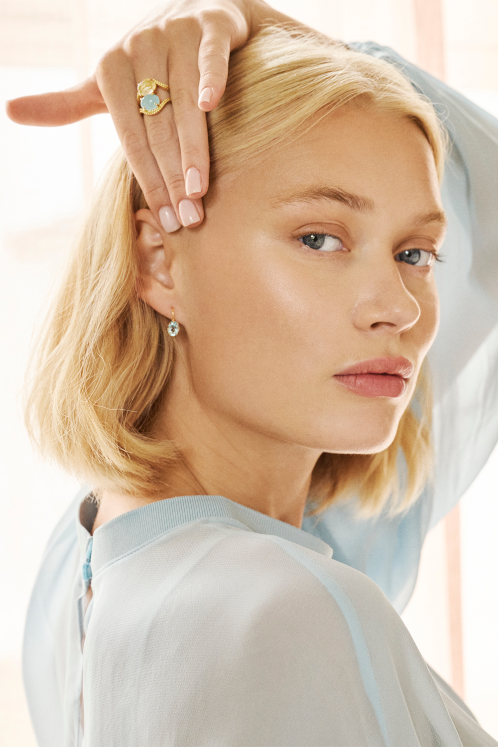 Ung kvinde med smykker i 10-karat ægte guld fra carré jewellery med ægte ædelsten i blå farver