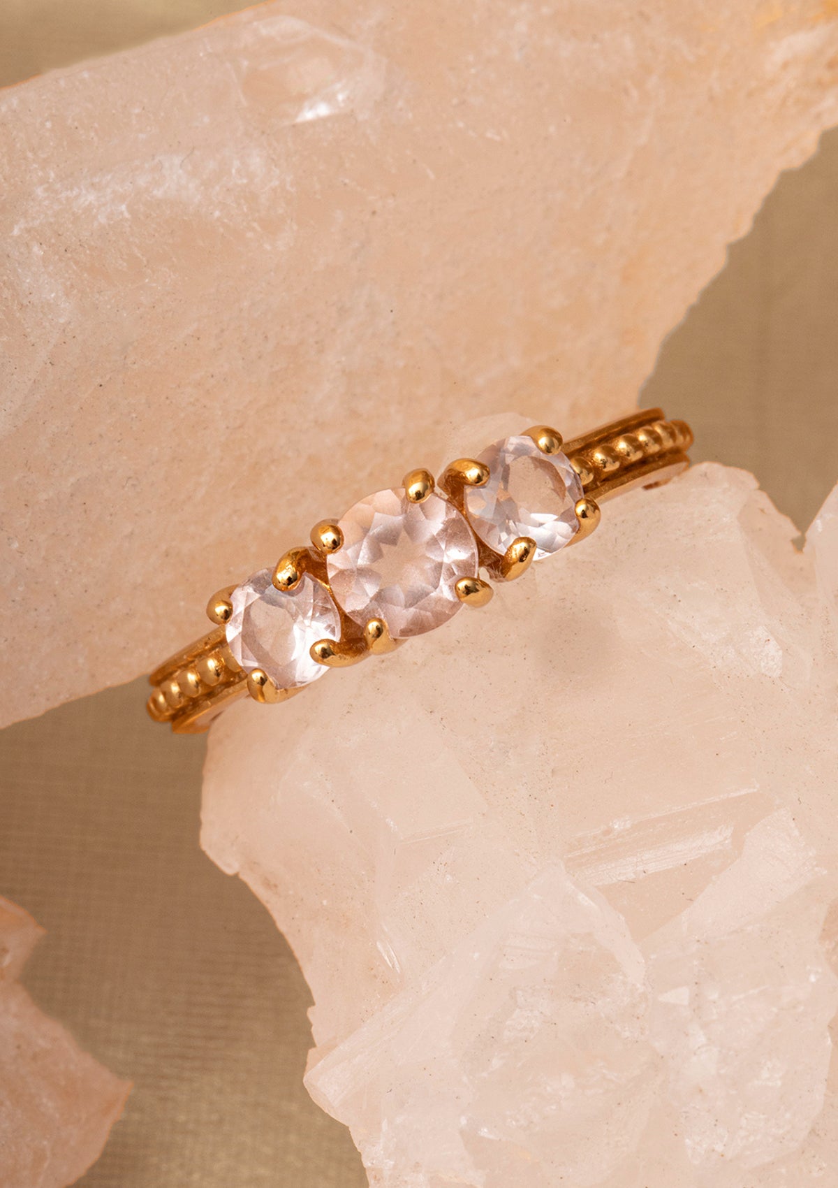Guldbelagt ring med tynd skinne sat med tre lyserøde ædelsten. Ædelstenene er Rosa Kvarts, der symboliserer kærlighed