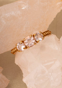 Guldbelagt ring med tynd skinne sat med tre lyserøde ædelsten. Ædelstenene er Rosa Kvarts, der symboliserer kærlighed