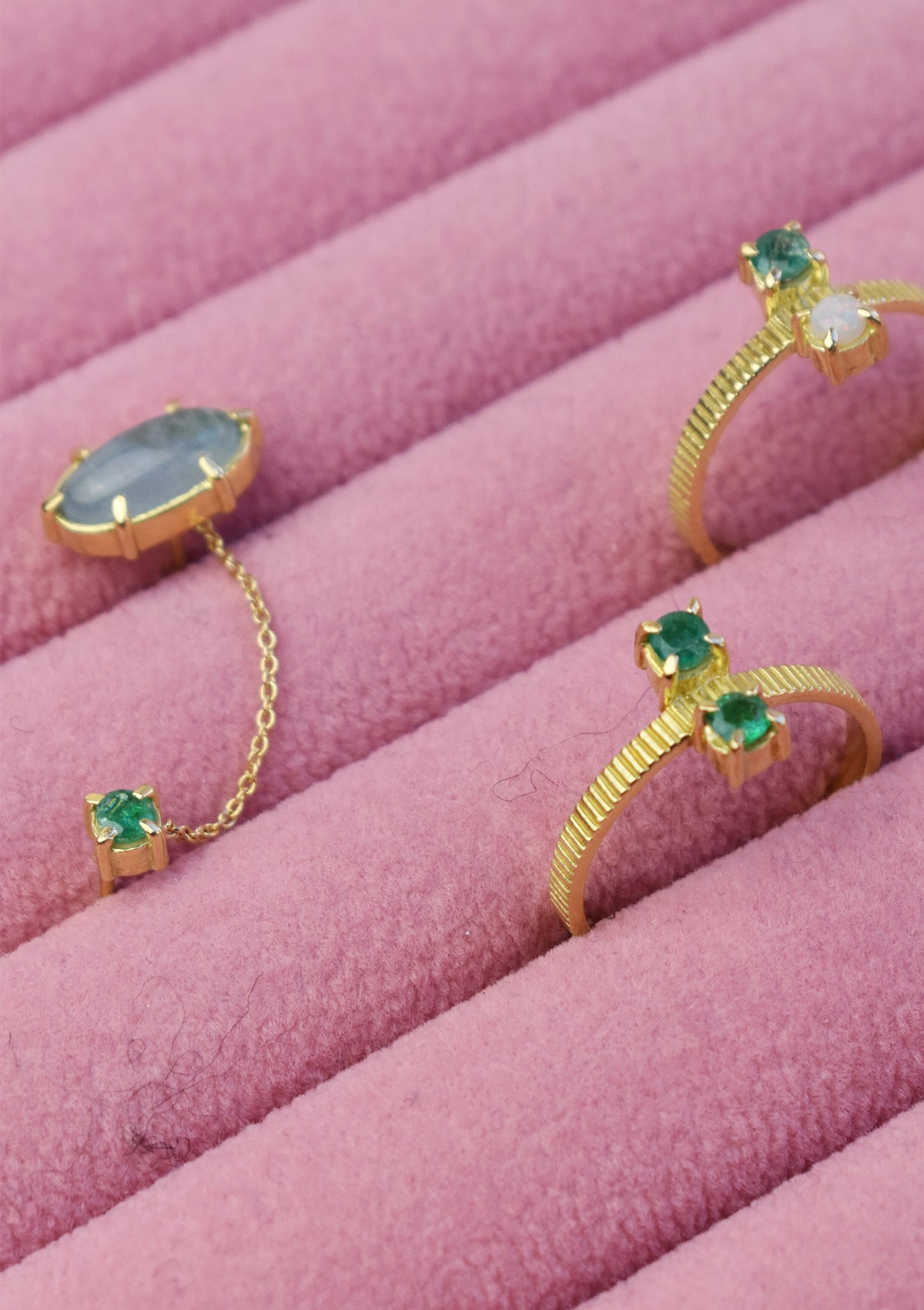 to ringe og en dobbelt ørestik med ædelsten i 18k guld. Alle er sat med smaragd
