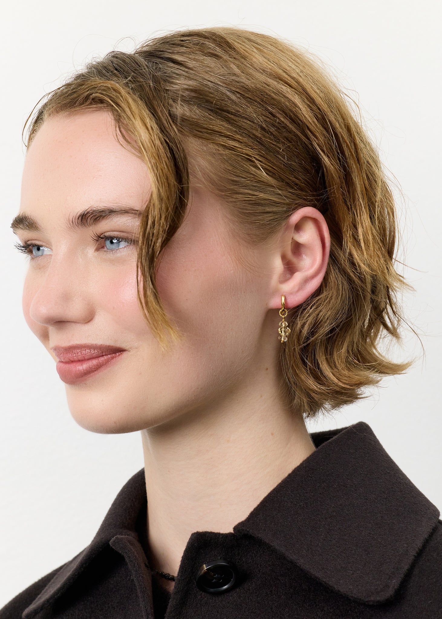 ung kvinde med hoop øreringe i guldbelagt sterling sølv med et charm med novembers fødselssten, citrin ædelsten fra carré jewellery