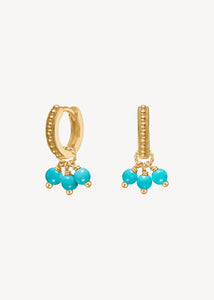 Triad huggie hoops og charms fra carré jewellery i guldbelagt sterling sølv med to byzantisk inspirerede hoops og to charms med turkis ædelsten, der er decembers fødselssten.