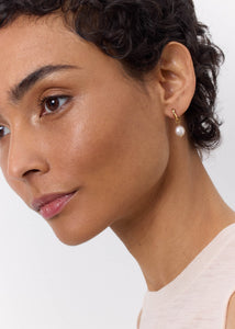 Kvinde med perleøreringe i guld fra carré jewellery til mænd og kvinder i huggie stil 