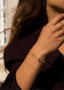 Kvinde med guldbelagte armbånd fra carré jewellery med grøn granat, ferskvandsperler og whisper armbånd uden sten 