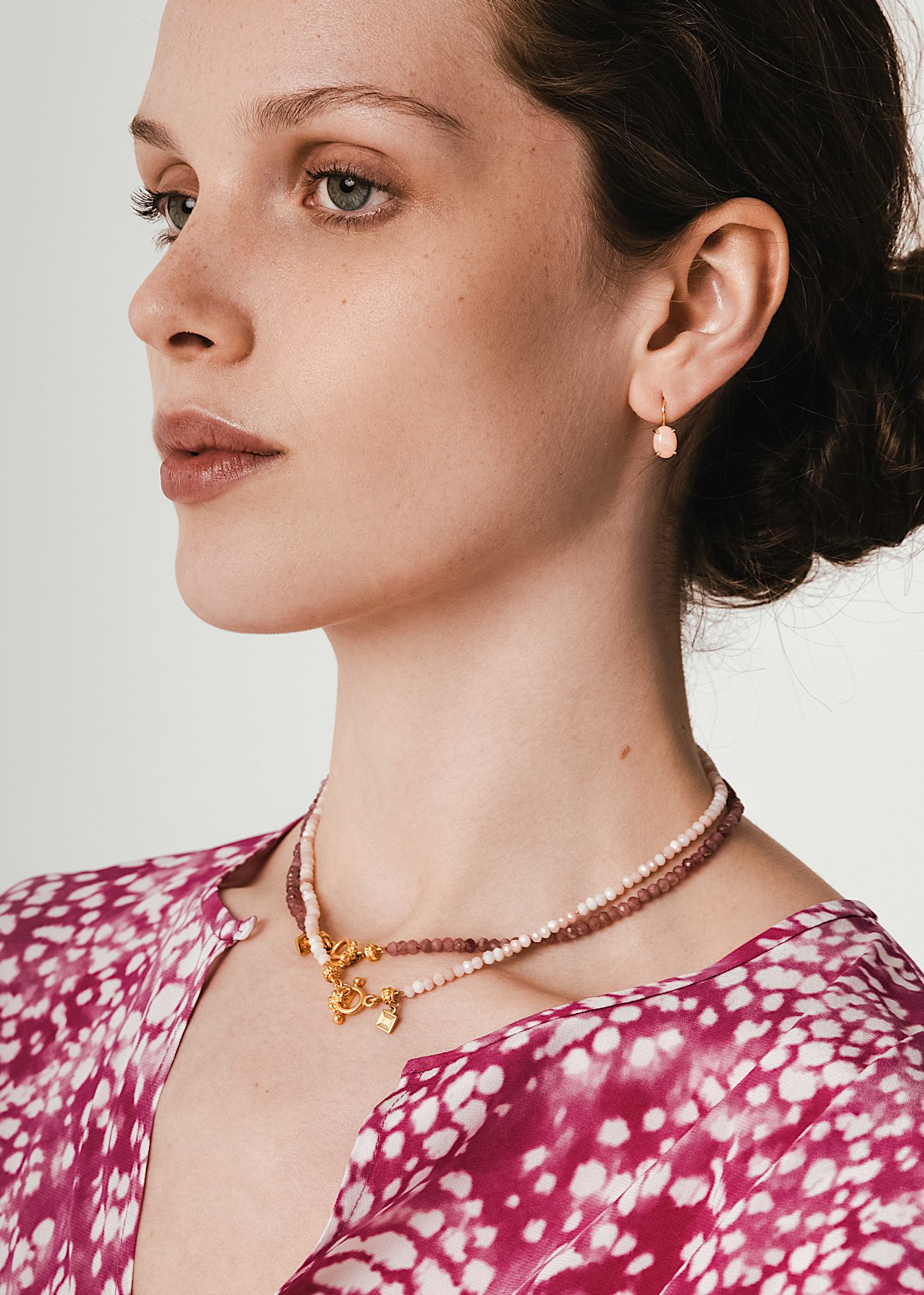 Kvinde med elegante øreringe med kroge i 10 karat ægte guld med en pink opal ædelsten i cabochonslibning 