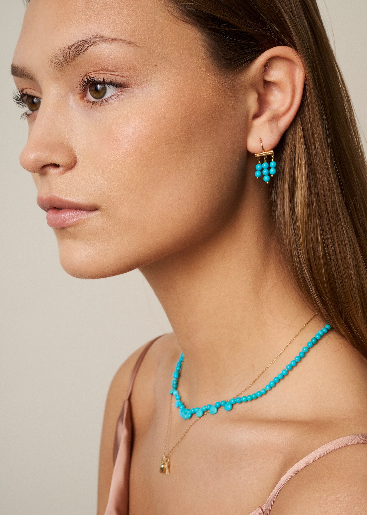 Ung kvinde med håndlavede sommersmykker med turkis ædelsten, der er decembers fødselssten fra carré jewellery i guldbelagt sterling sølv 