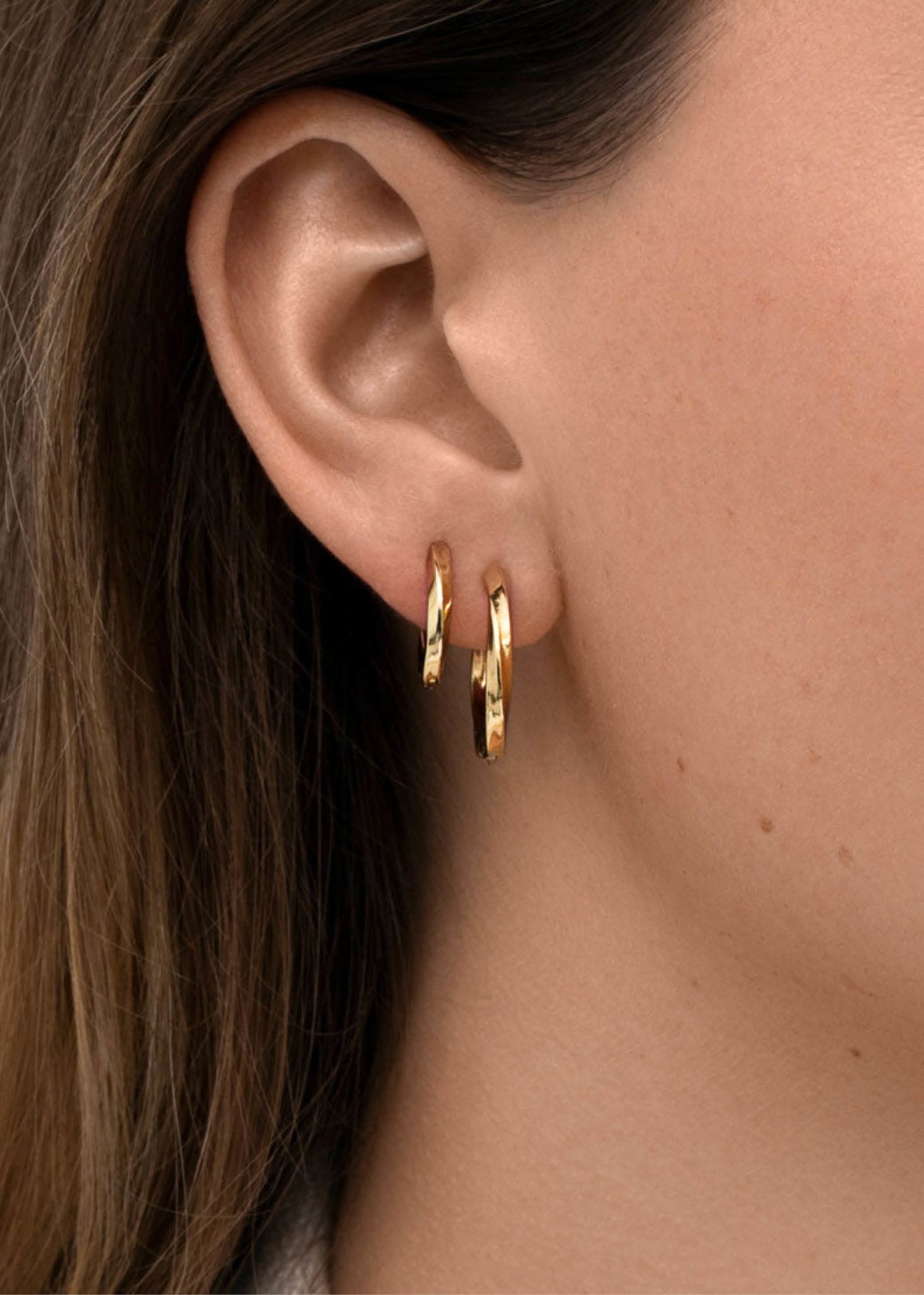 Kvinde med 1,5 og 2 cm snoede hoops med kliklås fra carré jewellery i guld 