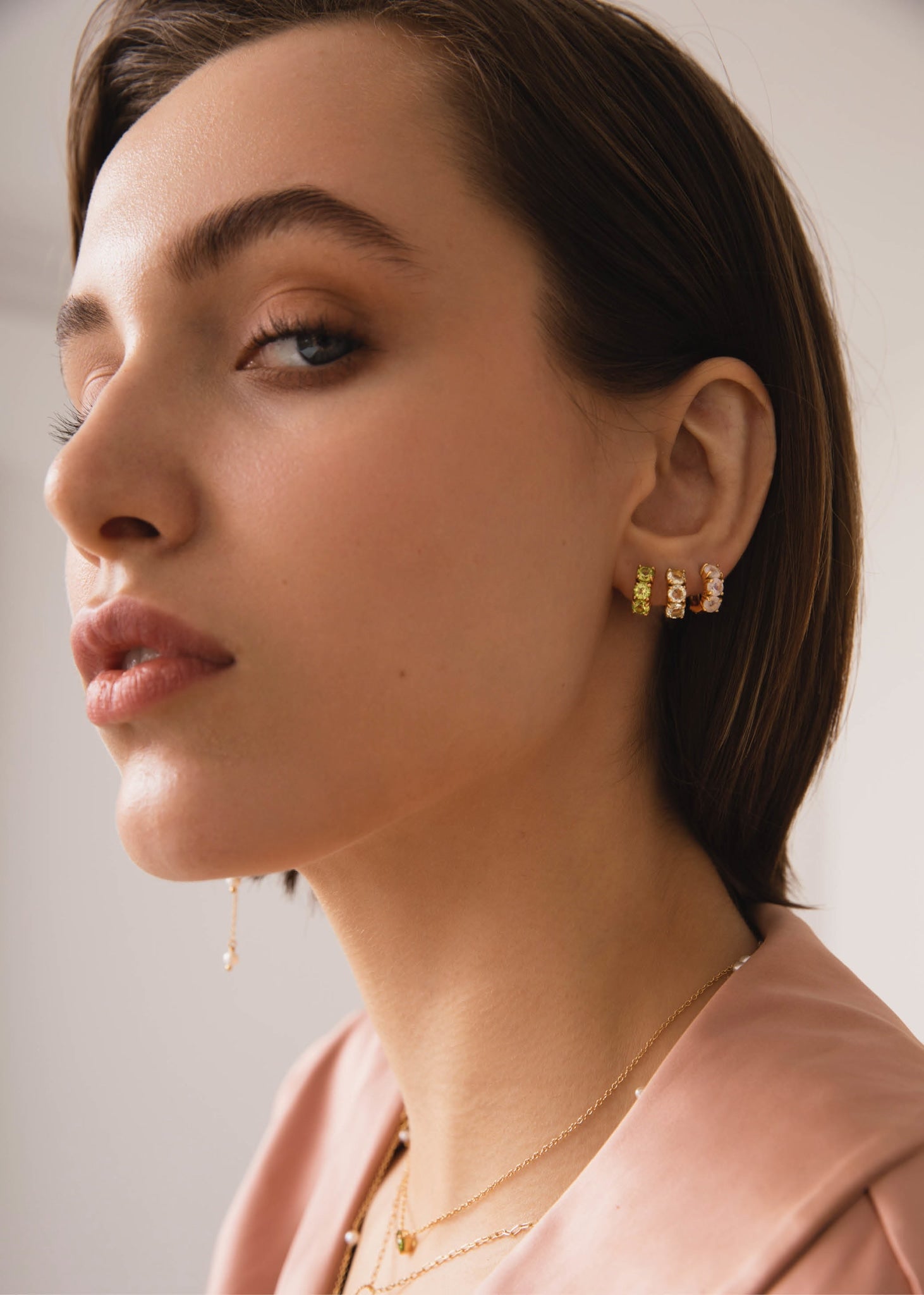 Kvinde med tre gem huggie hoops fra carré jewellery i guld med peridot, rosa kvarts og månesten ædelsten i facet