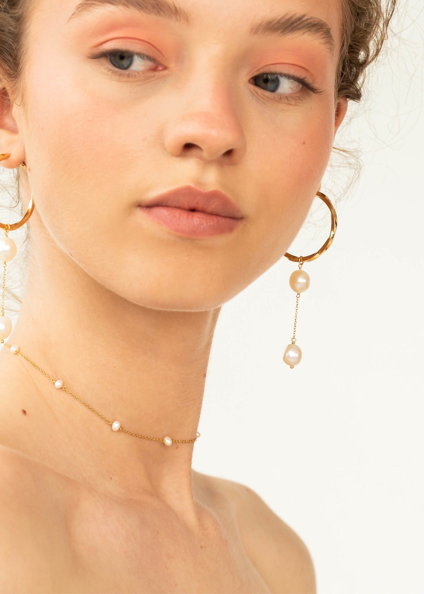Kvinde med store hoop øreringe og charm til øreringe med ferskvandsperler i guld fra carré jewellery 