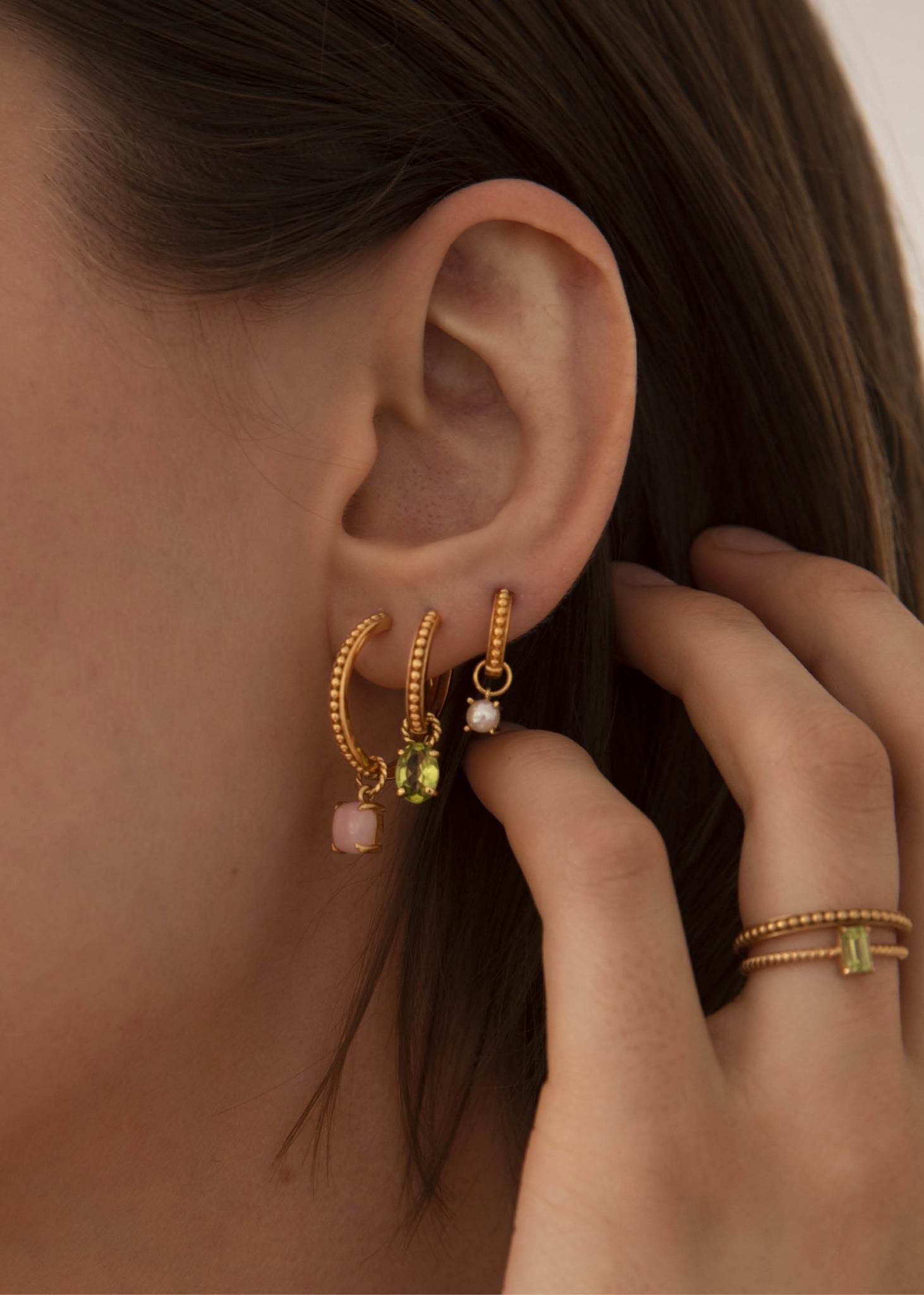Kvinde med hoops og charms fra carré jewellery med farverige ægte ædelsten i pink opal, ferskvandsperle og grøn peridot ædelstene