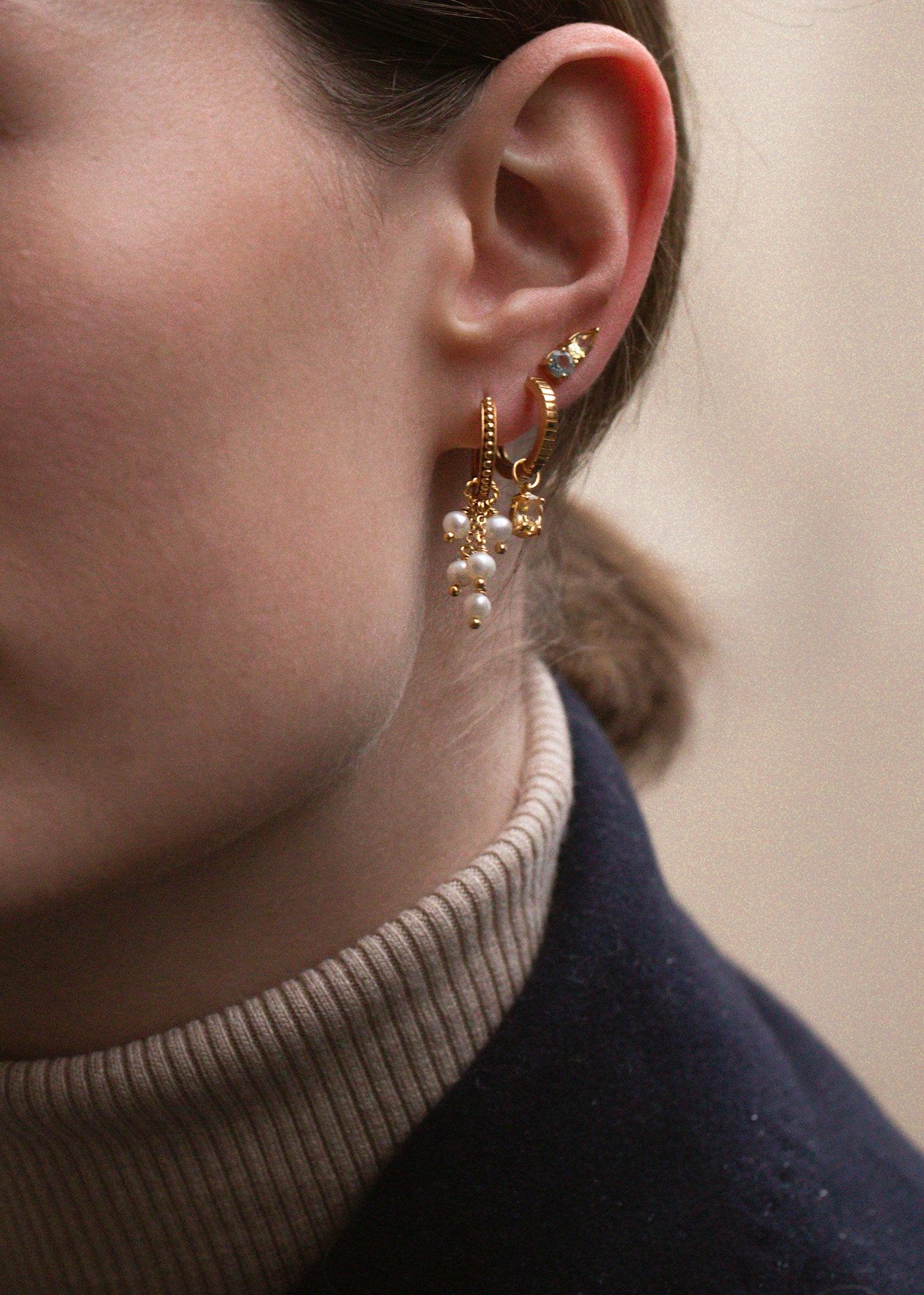 Kvinde med hoops og charms i guldbelagt sølv fra carré jewellery med lange hængeøreringe i guld med ferskvandsperler