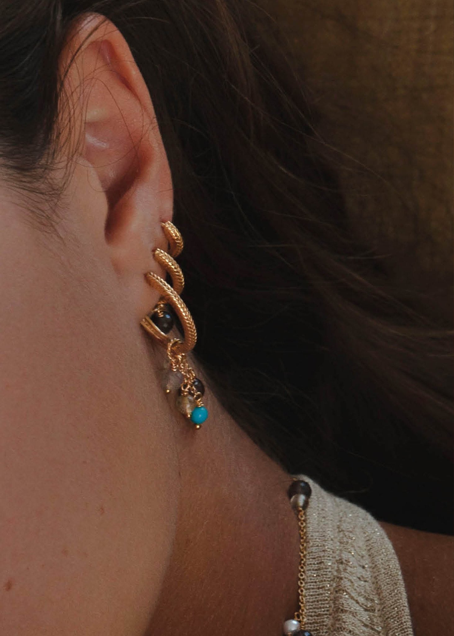 Kvinde med lange hængeøreringe i guld med blandede ædelsten fra carré Jewellery