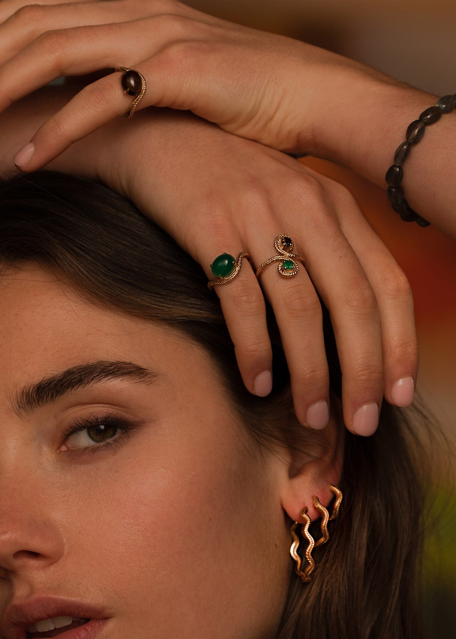 Kvinde med guld ringe fra carré jewellerys adorn kollektion med en eternity ring og to adorn ringe med brun kvarts og en grøn agat