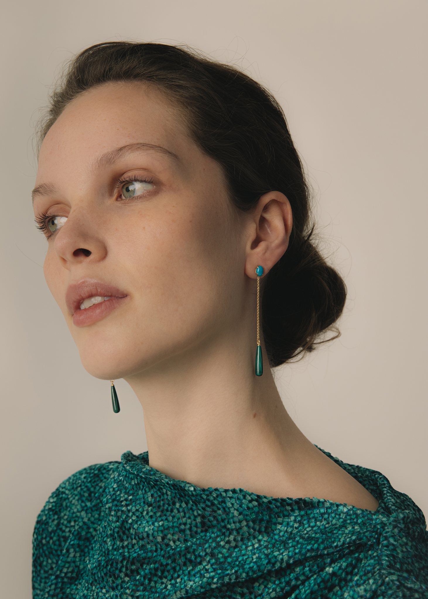 Ung kvinde med valle ørestikker fra carré jewellery, der er er håndlavet i københavn i guldbelagt sterling sølv med blå turkis ædelsten, en lang ankerkæde og grønne dråber af cabochonslebet Malakit ædelsten