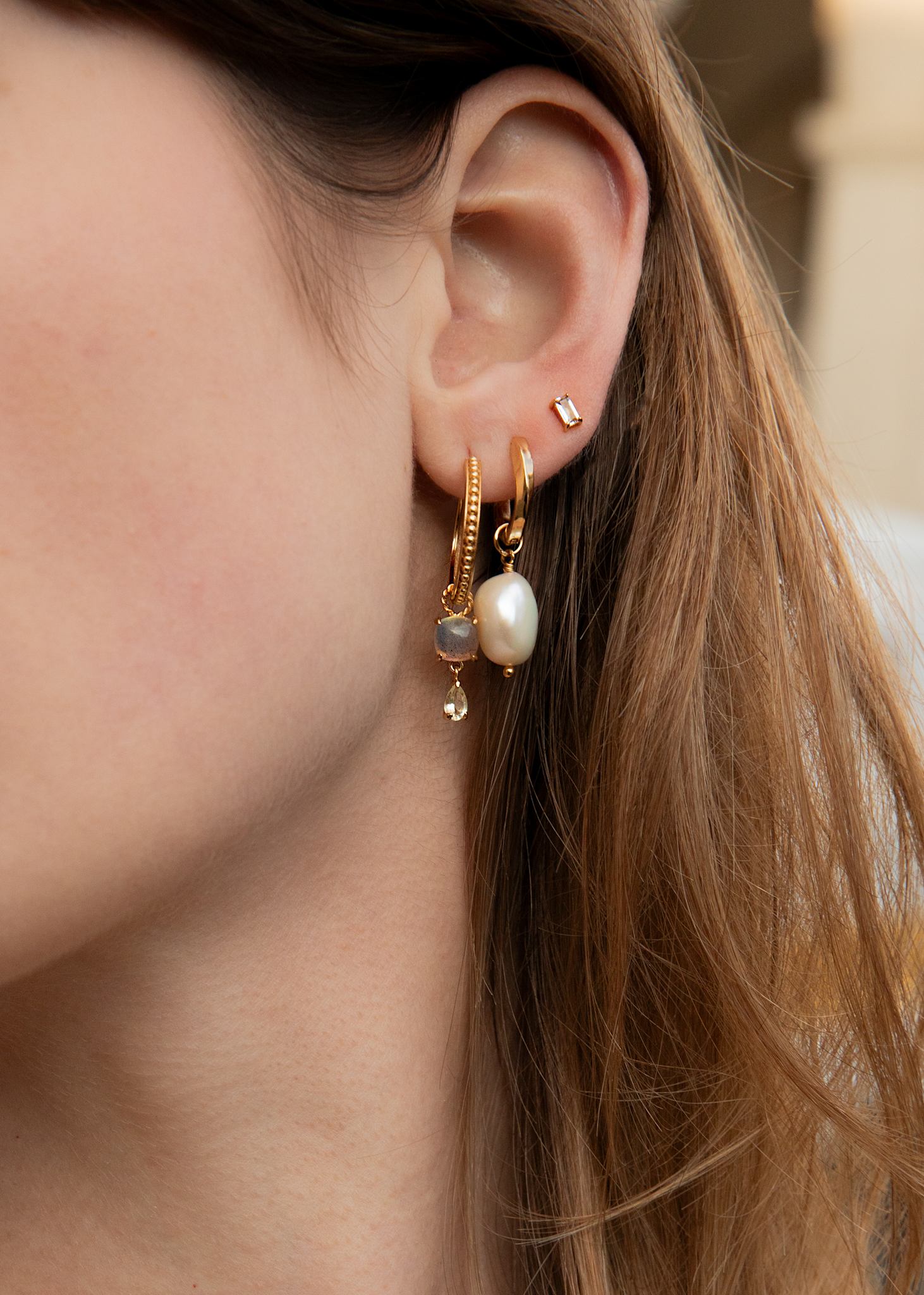 Kvinde med hoops og charms i guldbelagt sølv fra carré jewellery med ægte ferskvandsperler og labradorit og lemon kvarts ædelsten 