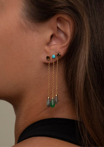Kvinde med lange øreringe fra Carré Jewellery med grønne, blå, grå og brune sten og lange guldkæder ørestikker