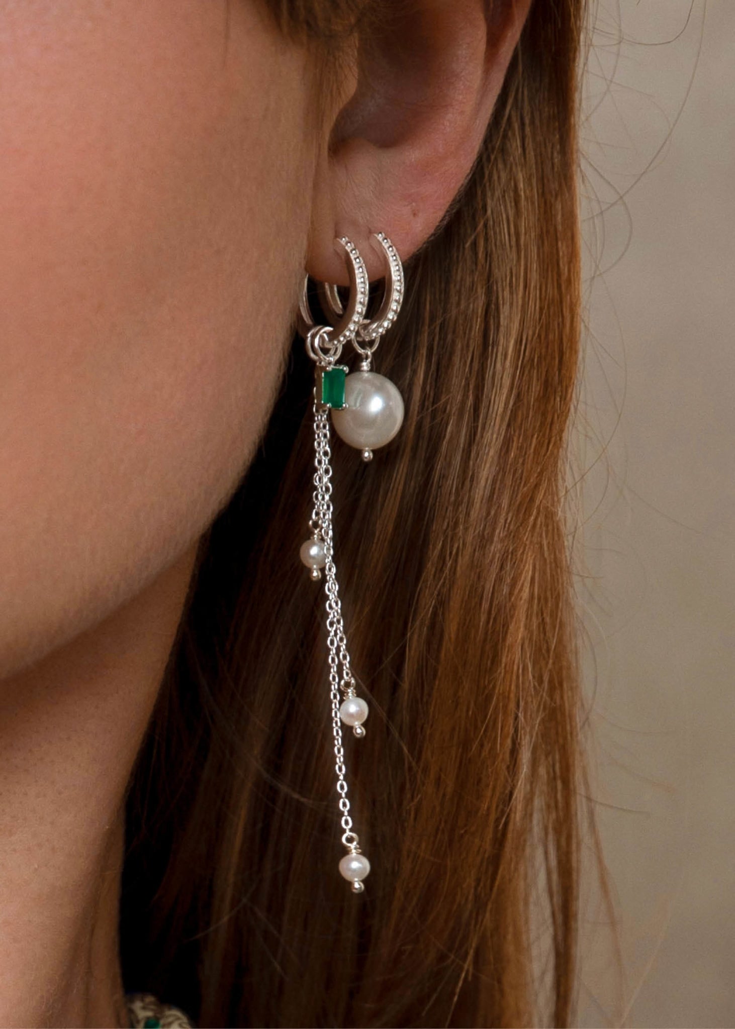 Kvinde med hoops og charms i sterling sølv fra carré jewellery med grønne sten og ferskvandsperler