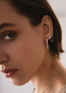Kvinde med hoops og charms til øreringe i sterling sølv med grøn peridot ædelsten charm fra carré jewellery - design dine egne øreringe i sølv her