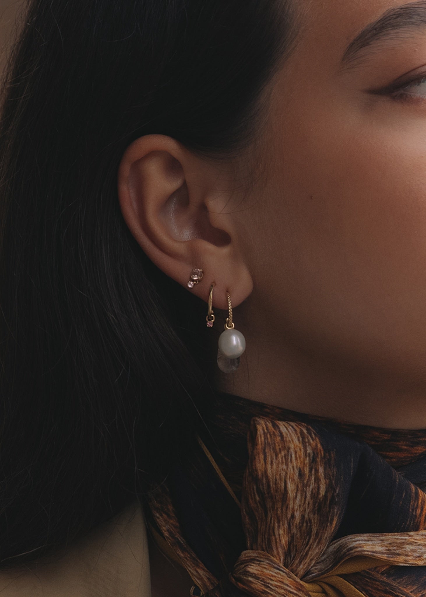 Kvinde med hoops og charms i 10 karat guld fra carré jewellery med lyserøde turmalin ædelsten og ferskvandsperle