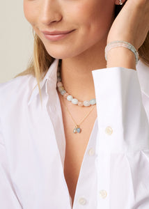Ung kvinde med stella vedhæng i ægte 10 karat guld fra carré jewellery med en blå topas ædelsten, der er november måneds fødselssten
