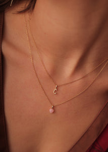 Kvinde med bogstavshalskæde i ægte guld med tre diamanter og bogstavet C og et hjertevedhæng i pink med diamanter i guld, perfekt gave til hende 