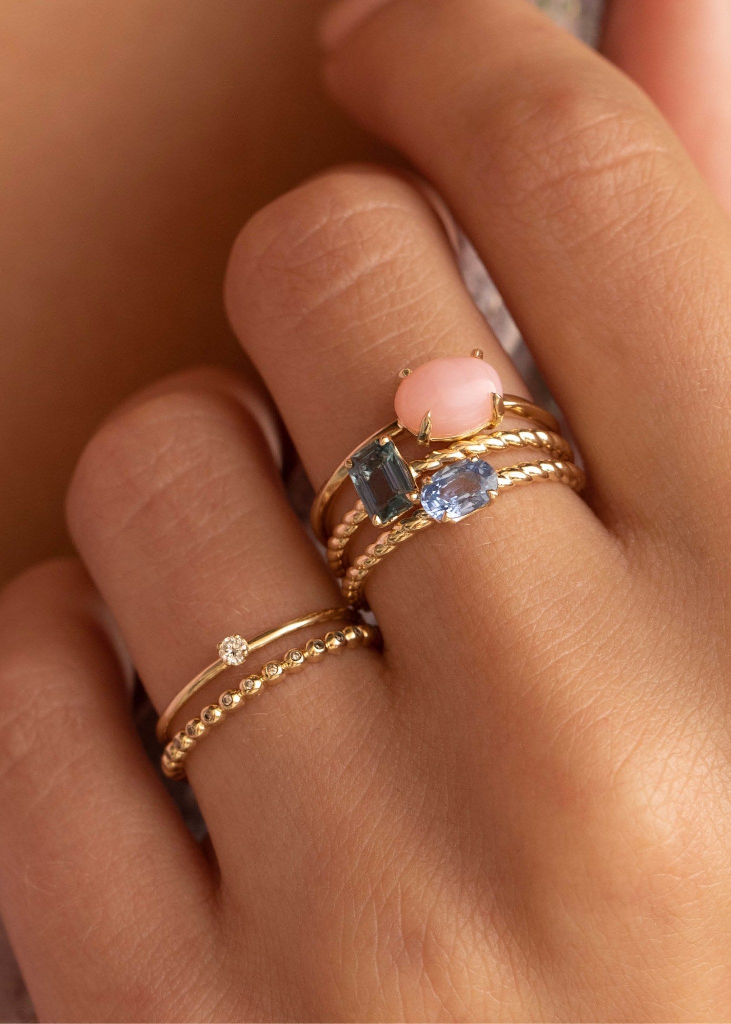 Kvinde med ringe i ægte 10 karat guld med pink opal, der er oktobers fødselssten