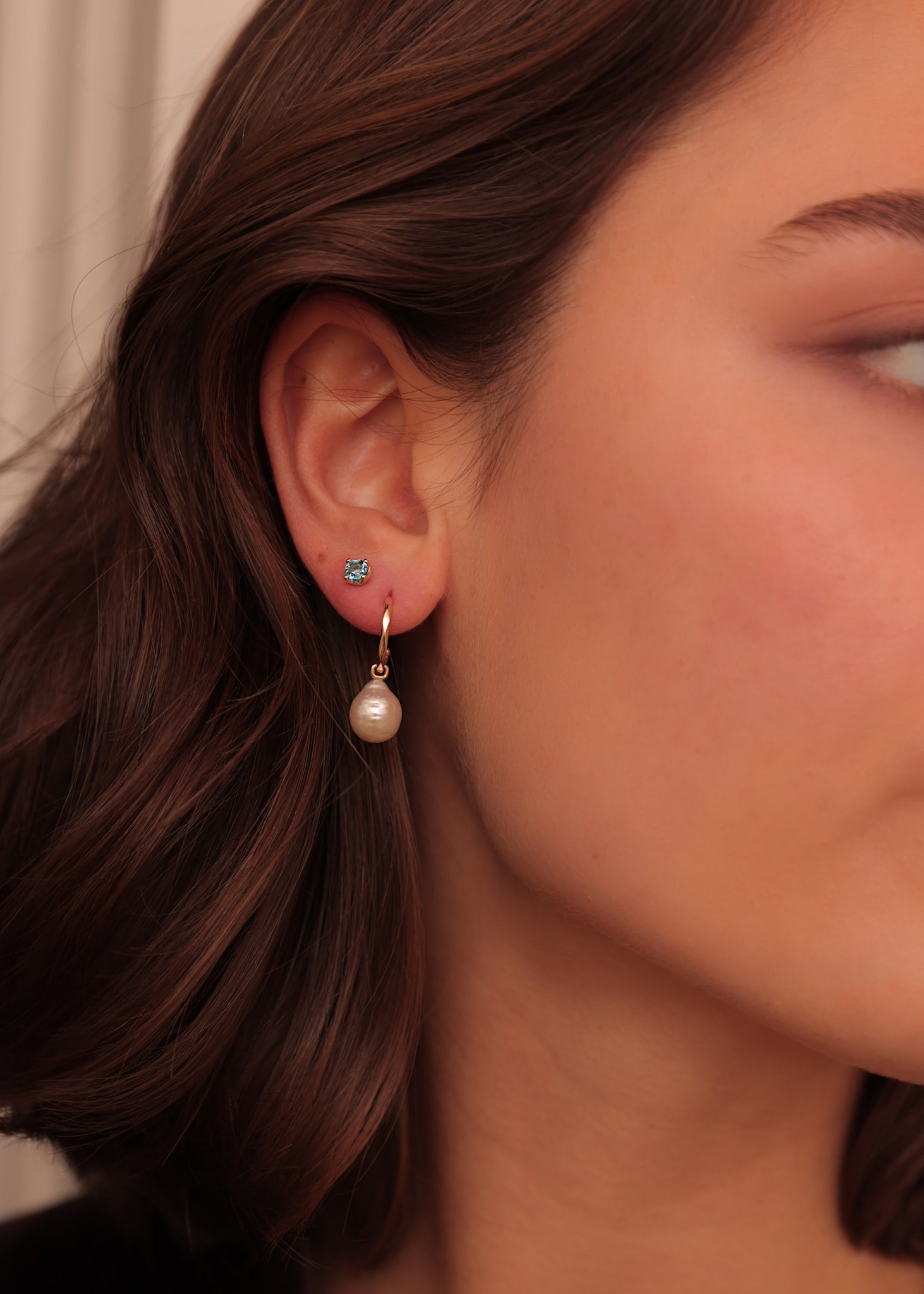 Ung kvinde med elegant lille ørestik med mørkeblå ædelsten, der hedder london blå topas i grabbefatning