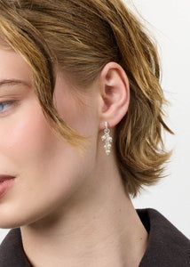 Kvinde med bloom øreringe fra carré jewellery i guldbelagt sølv med hvide ferskvandsperler og lange kæder på en hoop