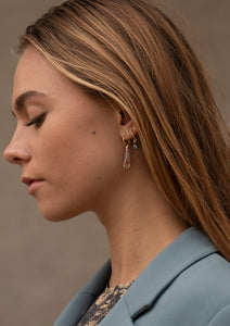 Kvinde med 10-karat hoops og charms fra Carré. Det ene charm er med en lang citrin ædelsten og den anden med en rund labradorit ædelsten