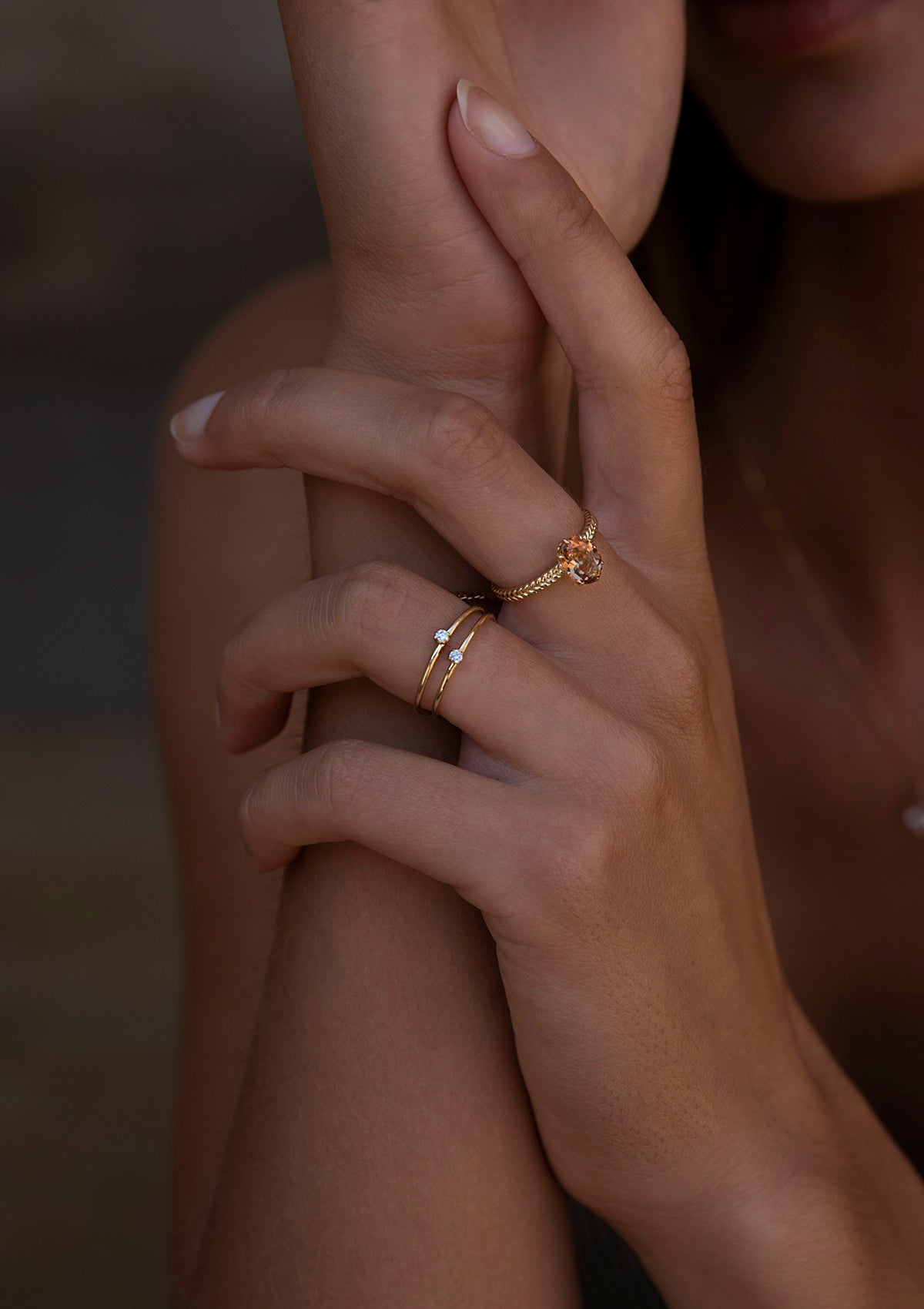 Kvinde med diamantringe fra carré i guld. Kvinden bærer også en ring med en stor champagne kvarts ædelsten