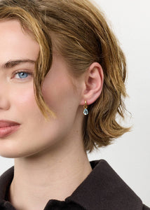 Ung kvinde med huggie hoops i guldbelagt sølv med store blå topas dråber fra carré jewellery