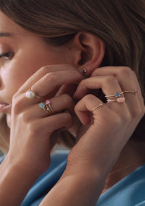 Kvinde med guld ringe fra carré i mange farver. En ring med blå safir, en ring med pink opal, en ring med perle mfl.