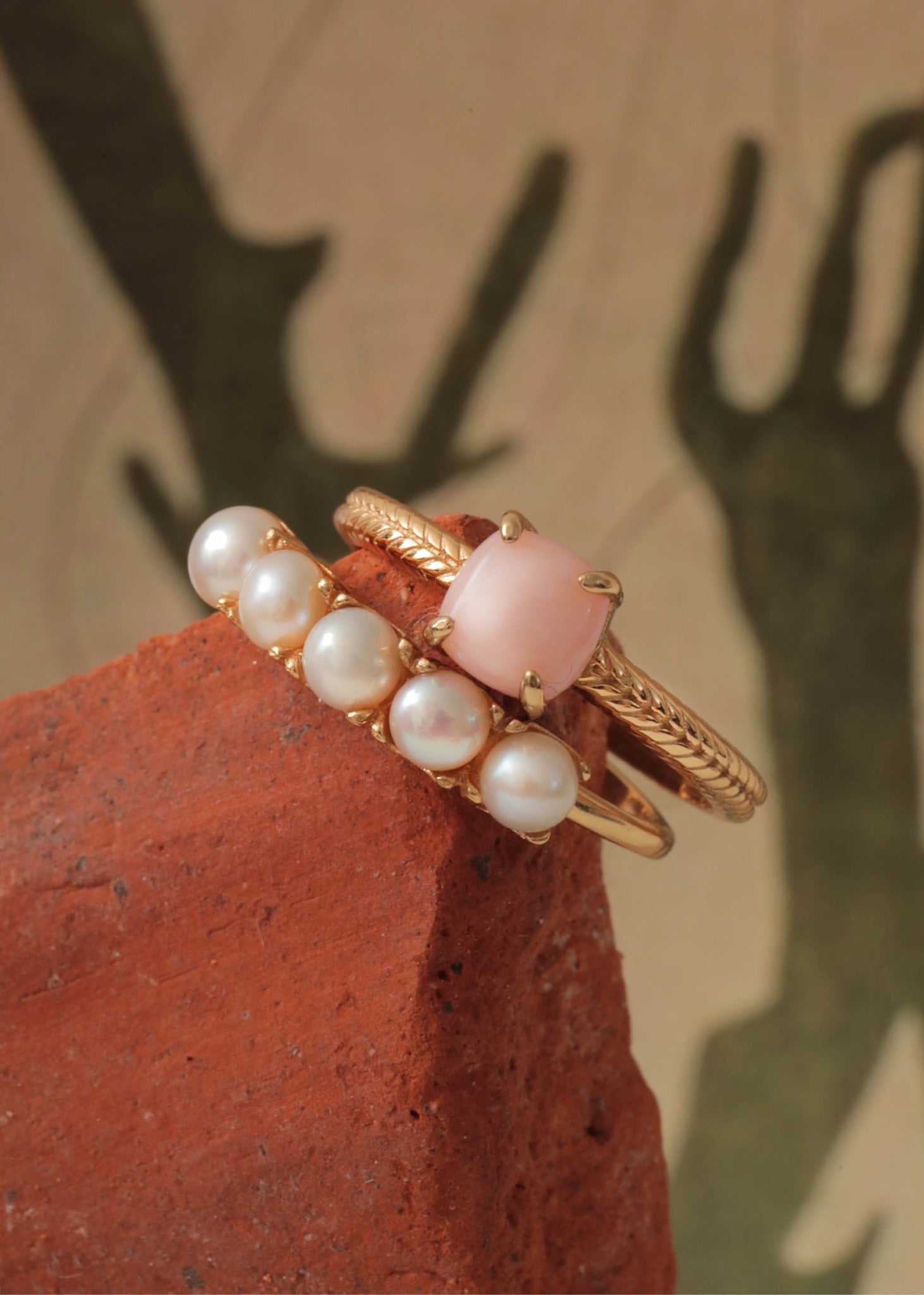 To ringe fra carré jewellery med sildebensmønster og hvide ferskvandsperler og en pink opal